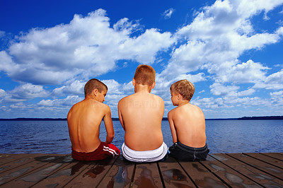 Three friends sitting together on a wooden deck