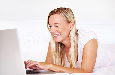 Beautiful middle aged lady using laptop on bed