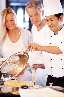 Happy cook serving food to mature couple