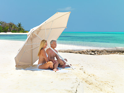 Mature couple on beach under umbrella