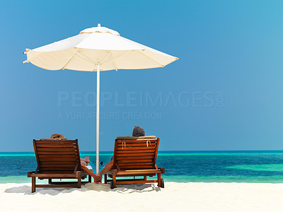 Couple resting on the deck chairs by the sea