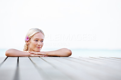 Young woman resting on the edge of pier by the sea