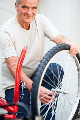 Happy mature man fixing a wheel of a cycle