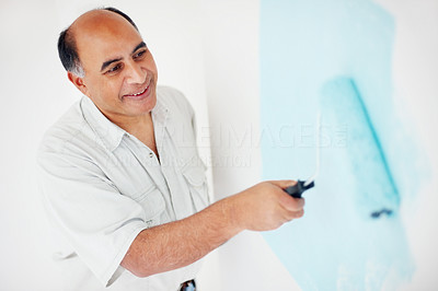 Smiling mature maintenance contractor painting the wall