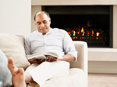 Mature man relaxing on a couch reading a book