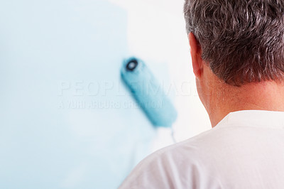 Closeup of a man painting a wall blue with a roller