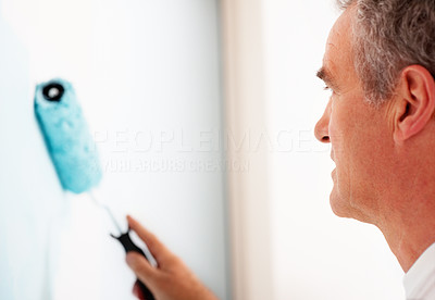Closeup of a mature man painting a wall blue