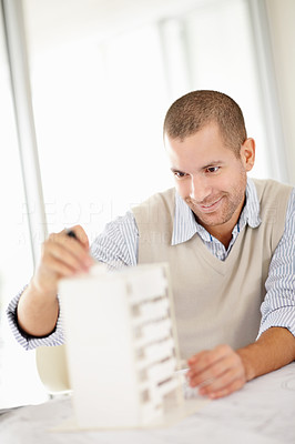 Middle aged architect busy planning on building model in office