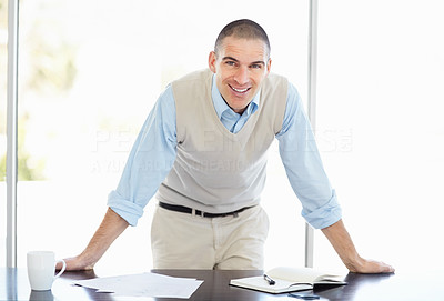 Happy middle aged man standing at his desk smiling