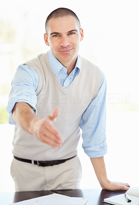Happy middle aged man at his desk giving you a handshake