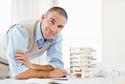Happy middle aged architect with a building model at office