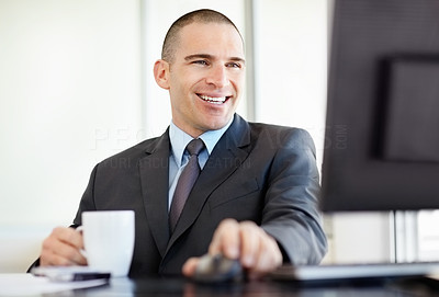 Middle aged business man holding coffee mug and using computer