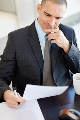 Smiling middle aged business man reading document at his desk