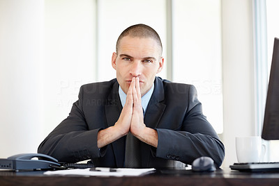 Thoughtful middle aged business man sitting in front of his desk