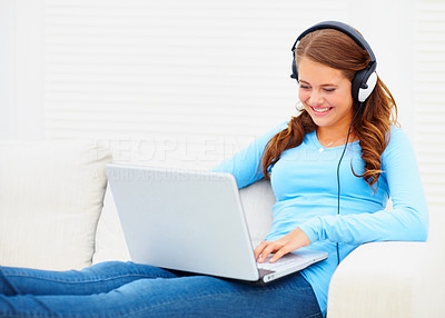 Cute teenaged girl enjoying the music on the laptop while at home