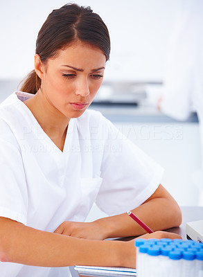 Female researcher sitting at a laboratory and writing notes