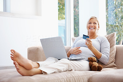 Joyful pregnant lady using credit card to shop from the internet