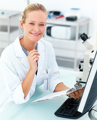 Smiling female researcher sitting at a laboratory and writing notes