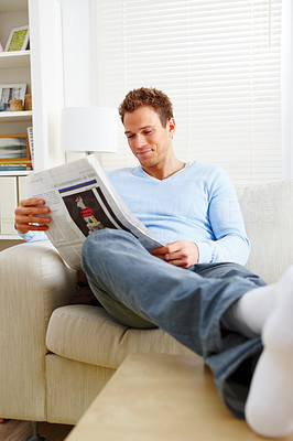 Happy man relaxing at home reading newspaper