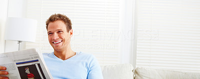 Man laughing at home reading newspaper