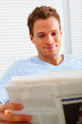 Closeup of a happy man at home reading newspaper