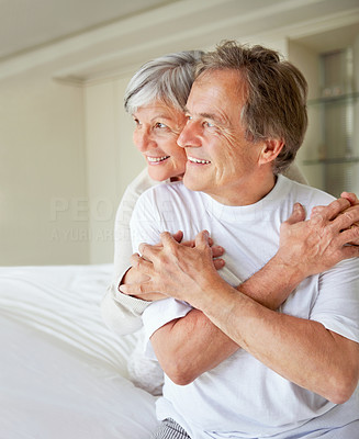 Elderly couple on bed looking away in thought