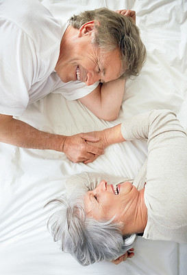Top view of a happy old couple holding hands in bed