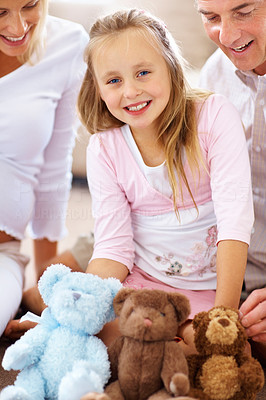 Happy family sitting on floor with soft toy in front