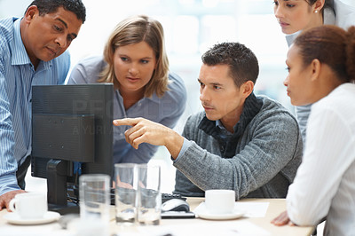 Teamwork - Business man pointing at laptop screen to team mates