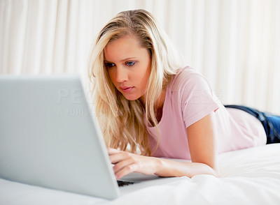 Cute young lady surfing the internet on bed