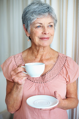 A senior woman with coffee cup looking away and smiling