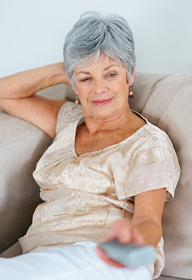 Relaxed elderly woman watching television while on sofa