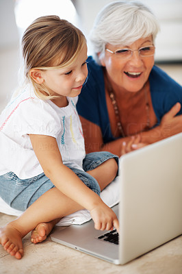 Woman using laptop with granddaughter