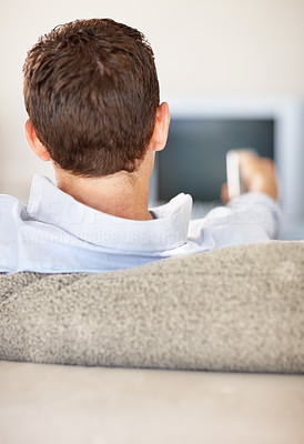 Rear view of a man holding remote control while watching TV