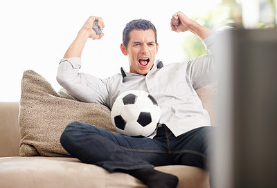 An excited middle aged man watching football match on television