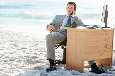 Middle aged business man over the telephone at his desk on beach