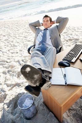 Relaxed middle aged business man with his legs on desk at beach