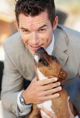 Happy middle aged business man getting a kiss from a cute puppy