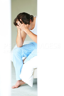 An upset young man sitting on a bed