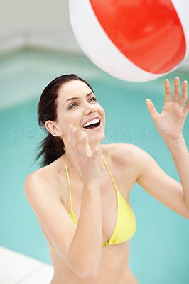 Happy female playing with ball by swimming pool