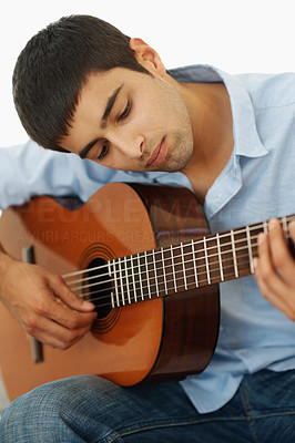 Young casual guy playing a guitar isolated against white