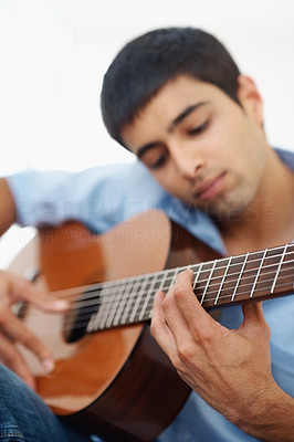 Young male musician playing a guitar isolated against white