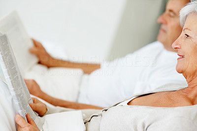 Relaxed senior couple lying and reading a magazine