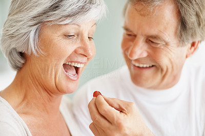 Romantic senior man giving a grape to a cute woman