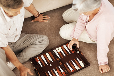 Senior couple playing backgammon on the floor