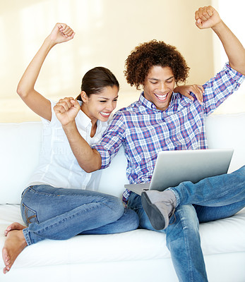 A young ethnic couple celebrating over something on the laptop