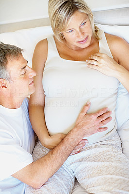 Top view of a pregnant couple in bed , man holding wife\'s tummy