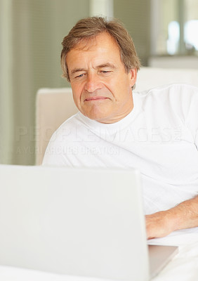 Elderly man working on a laptop while in bed