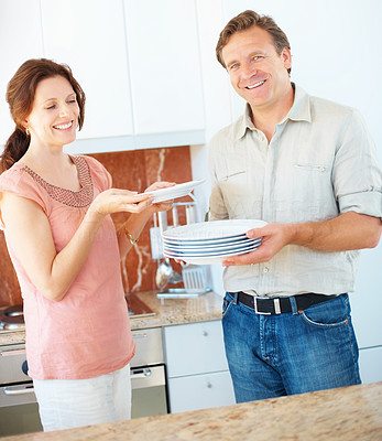 Happy mature couple during household chores in the kitchen