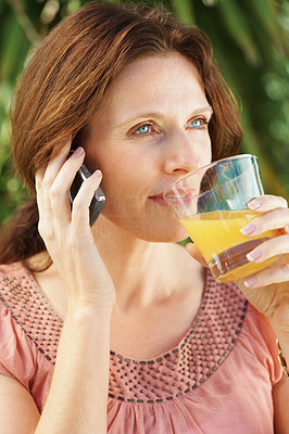 Beautiful mature woman with juice glass talking on the phone